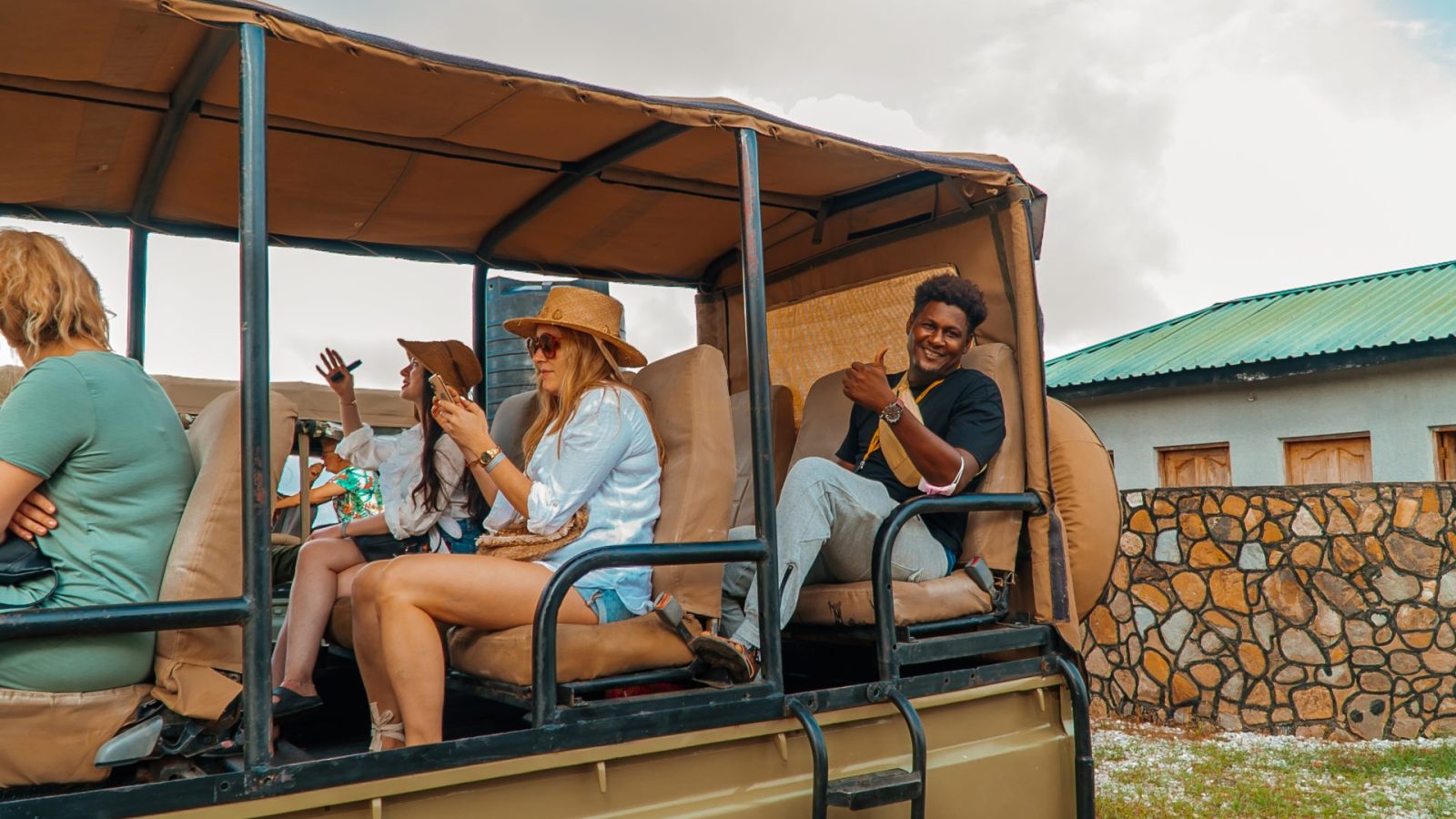 Guests and a smiling guide seated in an open-sided safari vehicle