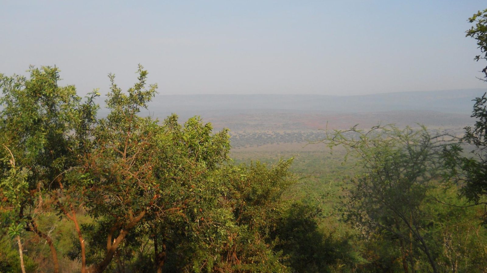 A view from a hilltop across a broad savannah valley