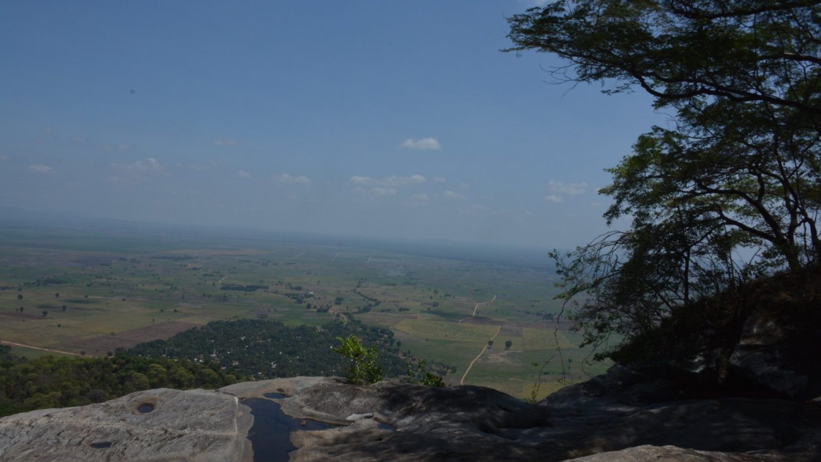 The view from a rocky escarpment out over plains far below